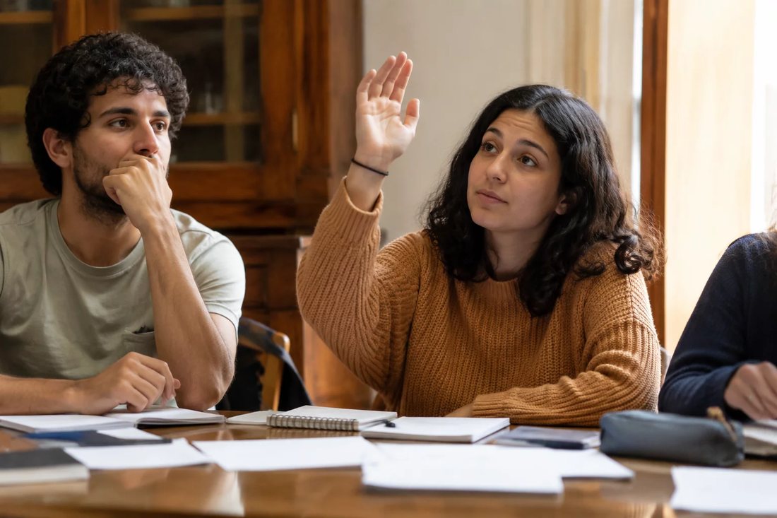 Facilitador de pé apontando para um argumento escrito no quadro durante a sessão